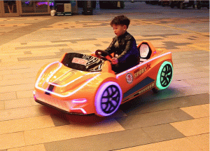 A colorful racing car kiddie ride designed for children, featuring bright colors and a sleek design, located in a playground setting.